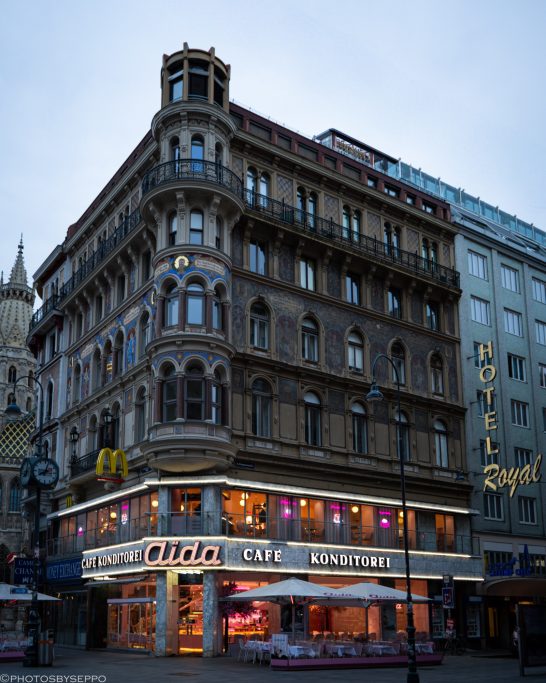 Historisches, mehrstöckiges Gebäude mit Schaufenstern und bunten Lichtern in einer Stadt.
