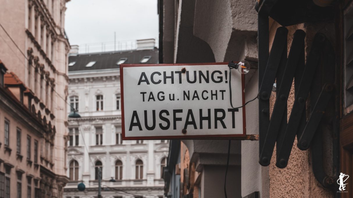 Schild mit der Aufschrift "Achtung Tag u. Nacht Ausfahrt" in einer Straßenansicht.