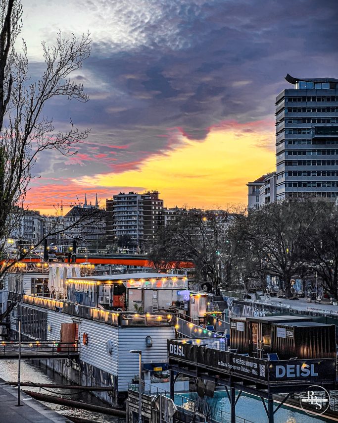 Stadtansicht mit Sonnenuntergang, bunten Lichtern und modernen Gebäuden.