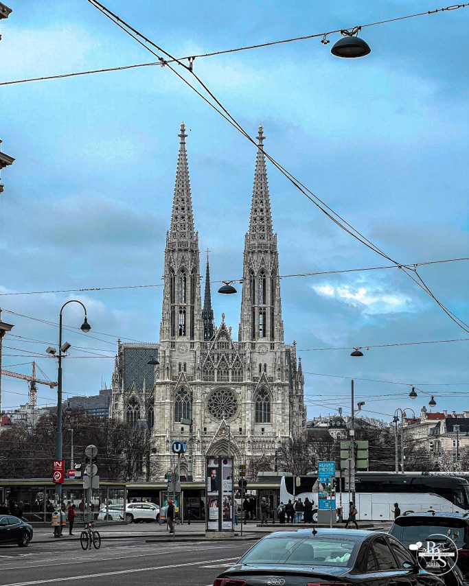 Bekanntes Kirchengebäude mit zwei spitzen Türmen und modernes Stadtumfeld.
