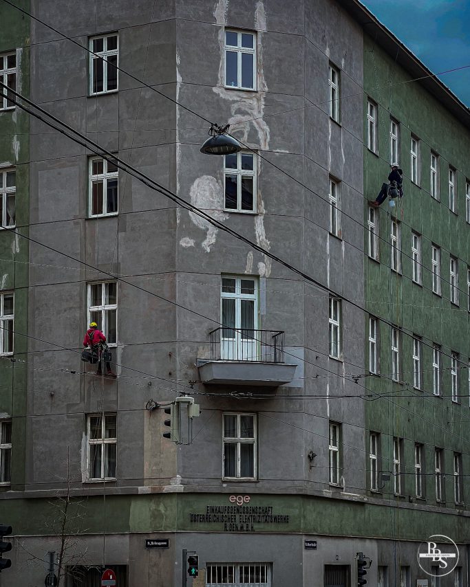 Handwerker reinigen die Fassade eines Gebäudes mit Graffiti in einer Stadt.
